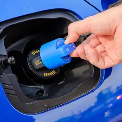 Dłoń zamyka niebieską nakrętkę z napisem AdBlue. To płyn do redukcji emisji spalin w dieslach.