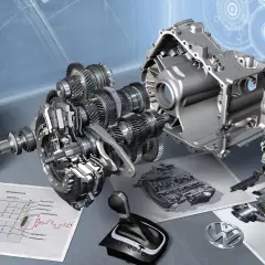 Rozłożona skrzynia DSG z widocznymi biegami, wałkami i schematem technicznym. Obok leży selektor biegów i logo VW.