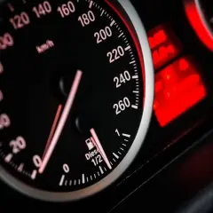 Zbliżenie na deskę rozdzielczą samochodu. Prędkościomierz pokazuje ok. 60 km/h. Wskaźnik paliwa jest na 1/2. Dowiedz się, jak obliczyć spalanie paliwa na 100 km.