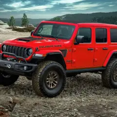 Czerwony Jeep Rubicon na kamienistym podłożu, gotowy na przygodę. Nawet przy wysokich **kosztach paliwa**, ten terenowy potwór oferuje niezapomniane wrażenia.