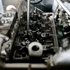 Wnętrze silnika z widocznymi zaworami i wtryskiwaczami. Mechanik sprawdza, czy nie występuje spalanie stukowe.
