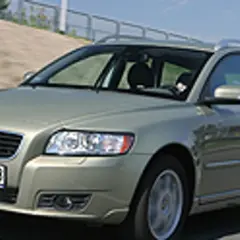 Złoty Volvo V50 2.0D na drodze, z widocznym kierowcą za kierownicą.