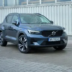 Elegancki, ciemnogranatowy Volvo XC40 2021 z charakterystycznymi światłami LED i felgami, zaparkowany przed budynkiem.
