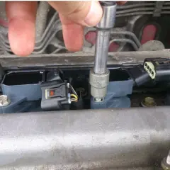 Naprawa zapłonu w Volkswagenie. Mechanik dokręca cewkę zapłonową, by rozwiązać problem DTC P0301.