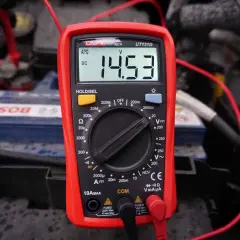 Multimetr pokazuje 14.53V DC, co jest kluczowe, jak sprawdzić alternator. Pomiar napięcia na akumulatorze podczas pracy silnika.