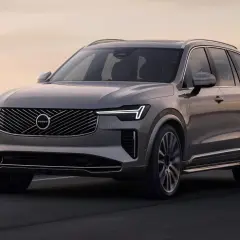 Elegancki, szary Volvo XC90 T8 sunie po drodze przy zachodzie słońca.