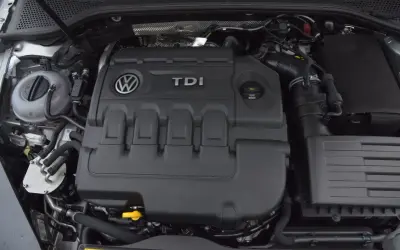 Silnik 2.0 TDI 190 KM. Widok na pokrywę silnika z logo VW i napisem TDI. W tle zbiornik płynu chłodniczego.