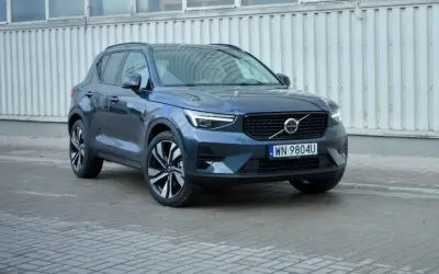 Elegancki, ciemnogranatowy Volvo XC40 2021 z charakterystycznymi światłami LED i felgami, zaparkowany przed budynkiem.