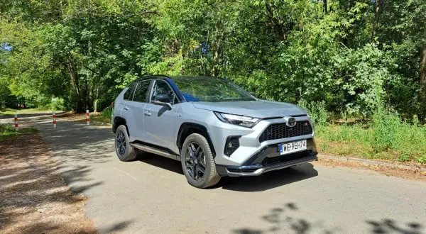 Srebrny Toyota RAV4 Hybrid na leśnej drodze. Zastanawiasz się nad jego spalaniem? Ten SUV oferuje świetne osiągi i niskie zużycie paliwa.