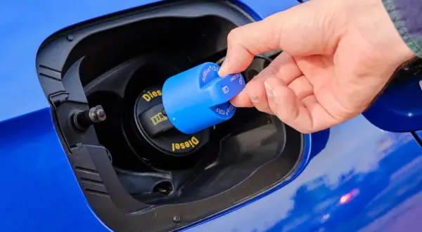 Dłoń zamyka niebieską nakrętkę z napisem AdBlue. To płyn do redukcji emisji spalin w dieslach.