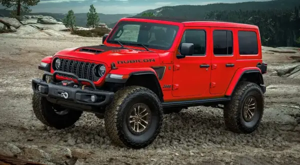 Czerwony Jeep Rubicon na kamienistym podłożu, gotowy na przygodę. Nawet przy wysokich **kosztach paliwa**, ten terenowy potwór oferuje niezapomniane wrażenia.