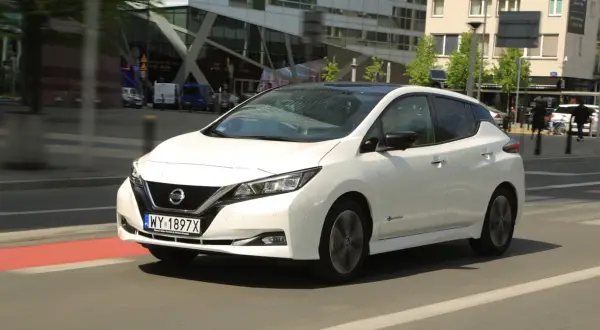 Biały Nissan Leaf 2 jedzie ulicą miasta.