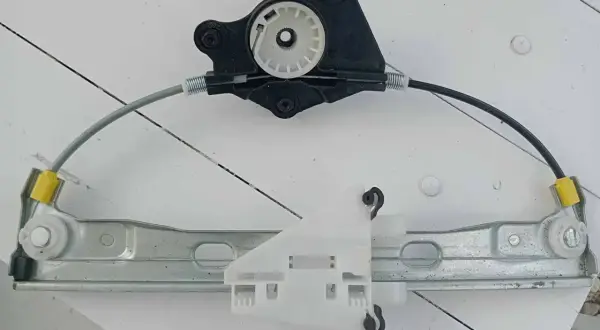 Mechanizm podnoszenia szyby, gotowy do wymiany. Składa się z metalowej szyny, linek i plastikowych elementów.