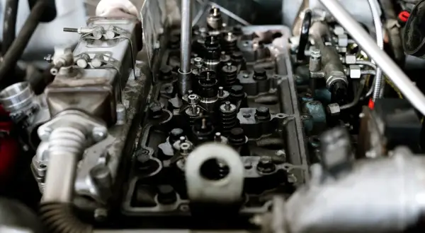 Wnętrze silnika z widocznymi zaworami i wtryskiwaczami. Mechanik sprawdza, czy nie występuje spalanie stukowe.