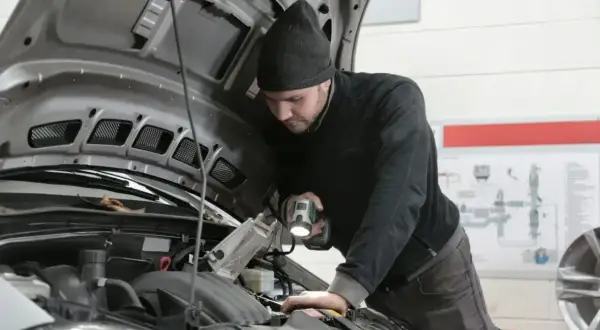 Mechanik z latarką bada silnik Renault, szukając przyczyny błędu DTC P0300.