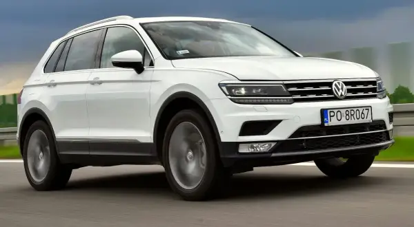 Biały Volkswagen Tiguan 2 jedzie po drodze.