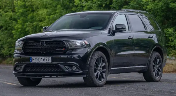 Czarny Dodge Durango 5.7 Hemi z polskimi tablicami rejestracyjnymi stoi na tle zieleni.