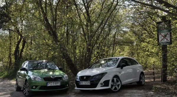 Zielony Skoda i biały Seat Bocanegra na leśnej drodze.