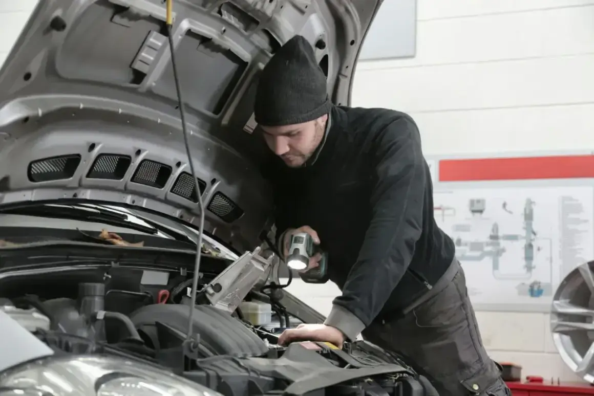 Mechanik z latarką bada silnik Renault, szukając przyczyny błędu DTC P0300.