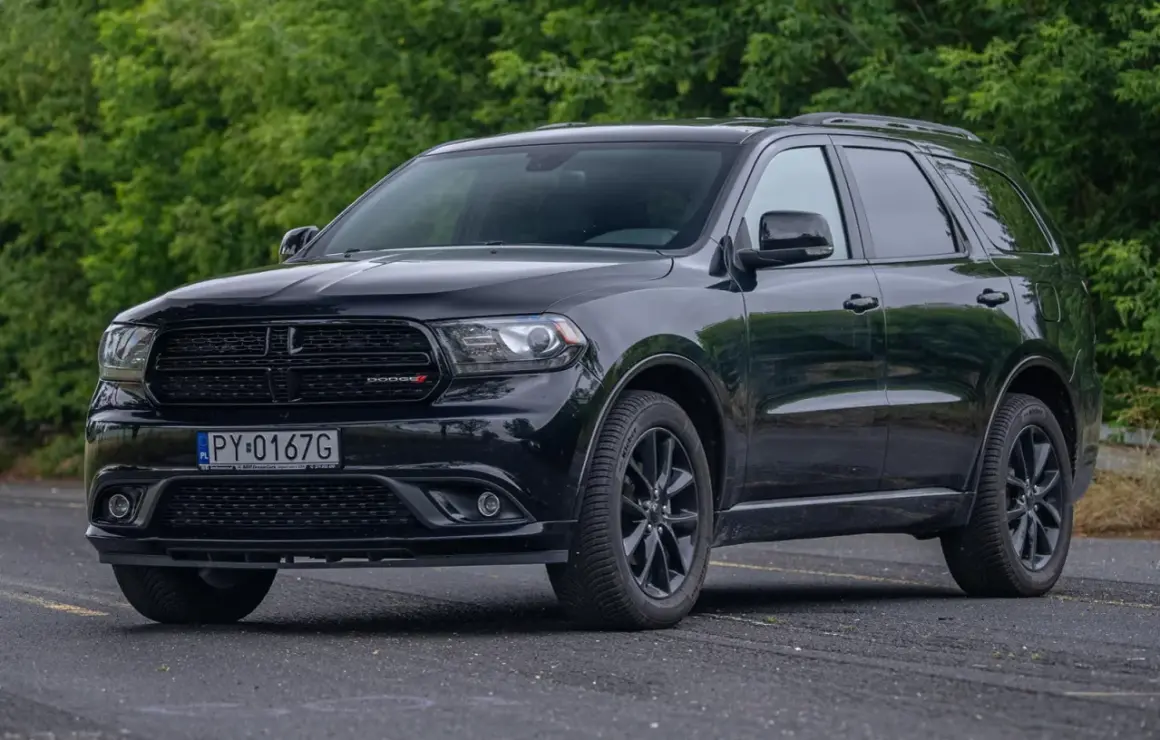 Czarny Dodge Durango 5.7 Hemi z polskimi tablicami rejestracyjnymi stoi na tle zieleni.