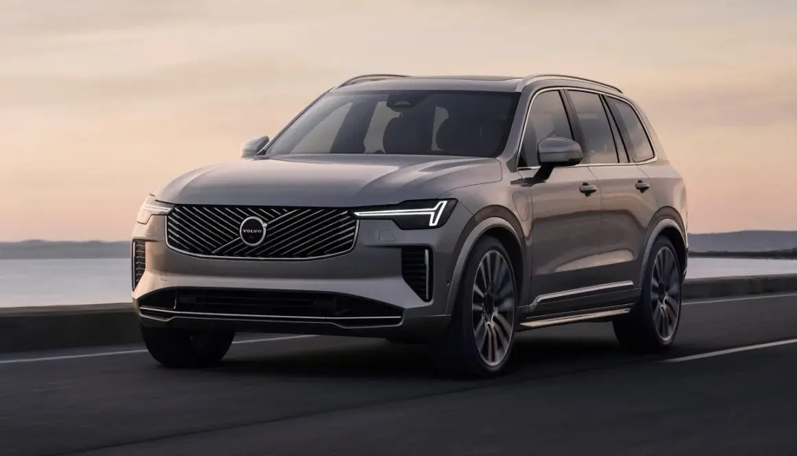 Elegancki, szary Volvo XC90 T8 sunie po drodze przy zachodzie słońca.