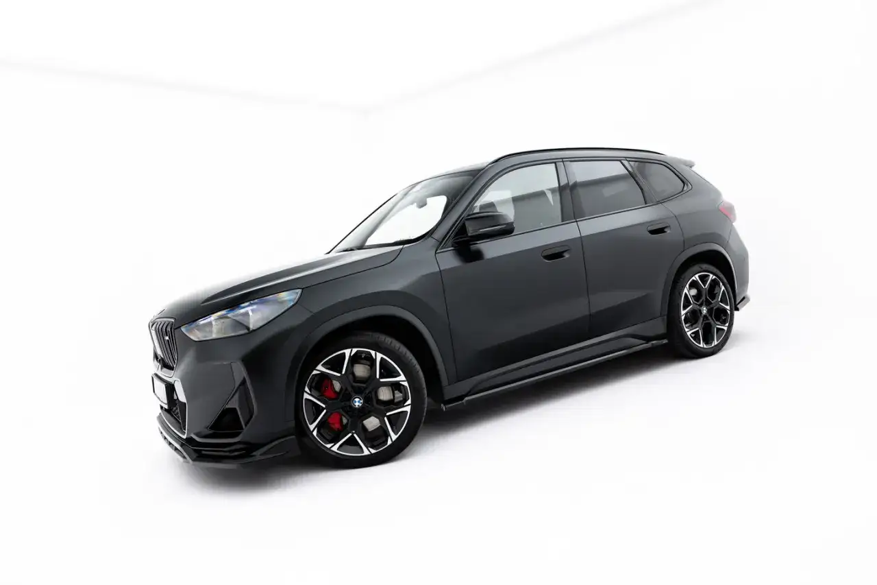 Ciemnoszary BMW X1 E84 z czarnymi dodatkami i czerwonymi zaciskami hamulcowymi, prezentujący sportowy charakter.