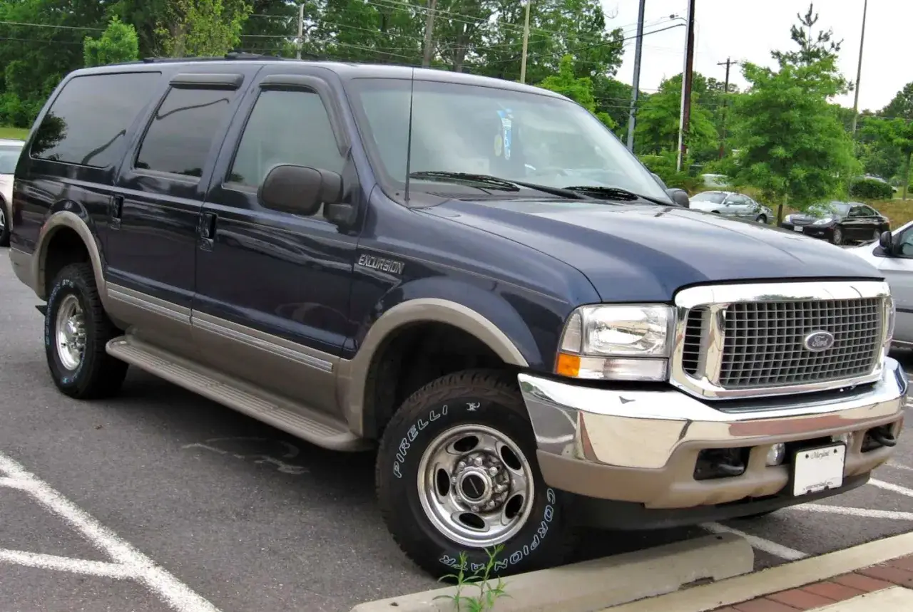 Ciemnoniebieski Ford Excursion z beżowymi akcentami, zaparkowany na parkingu.