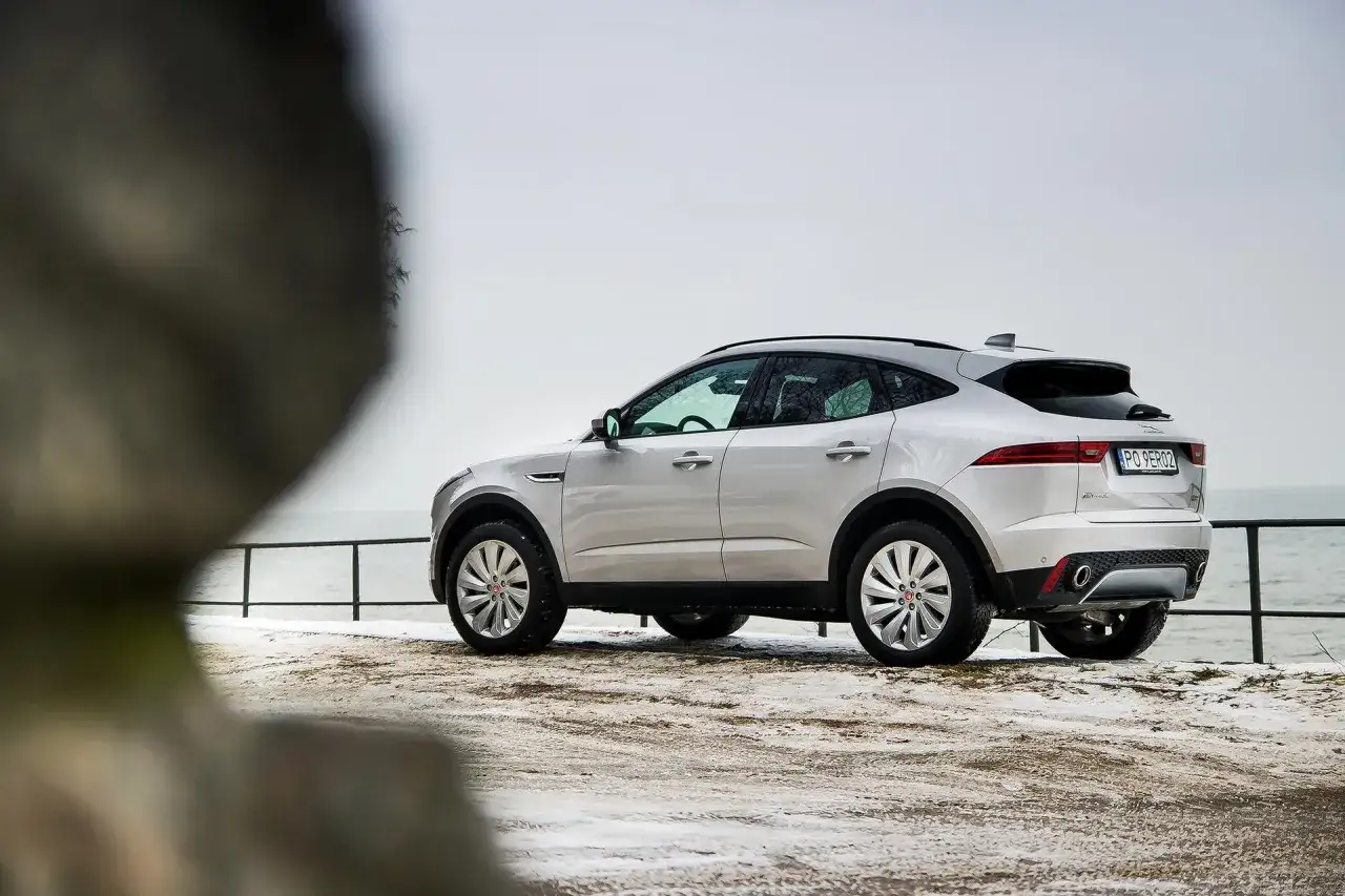 Srebrny Jaguar E-Pace na tle zimowego krajobrazu nad morzem.