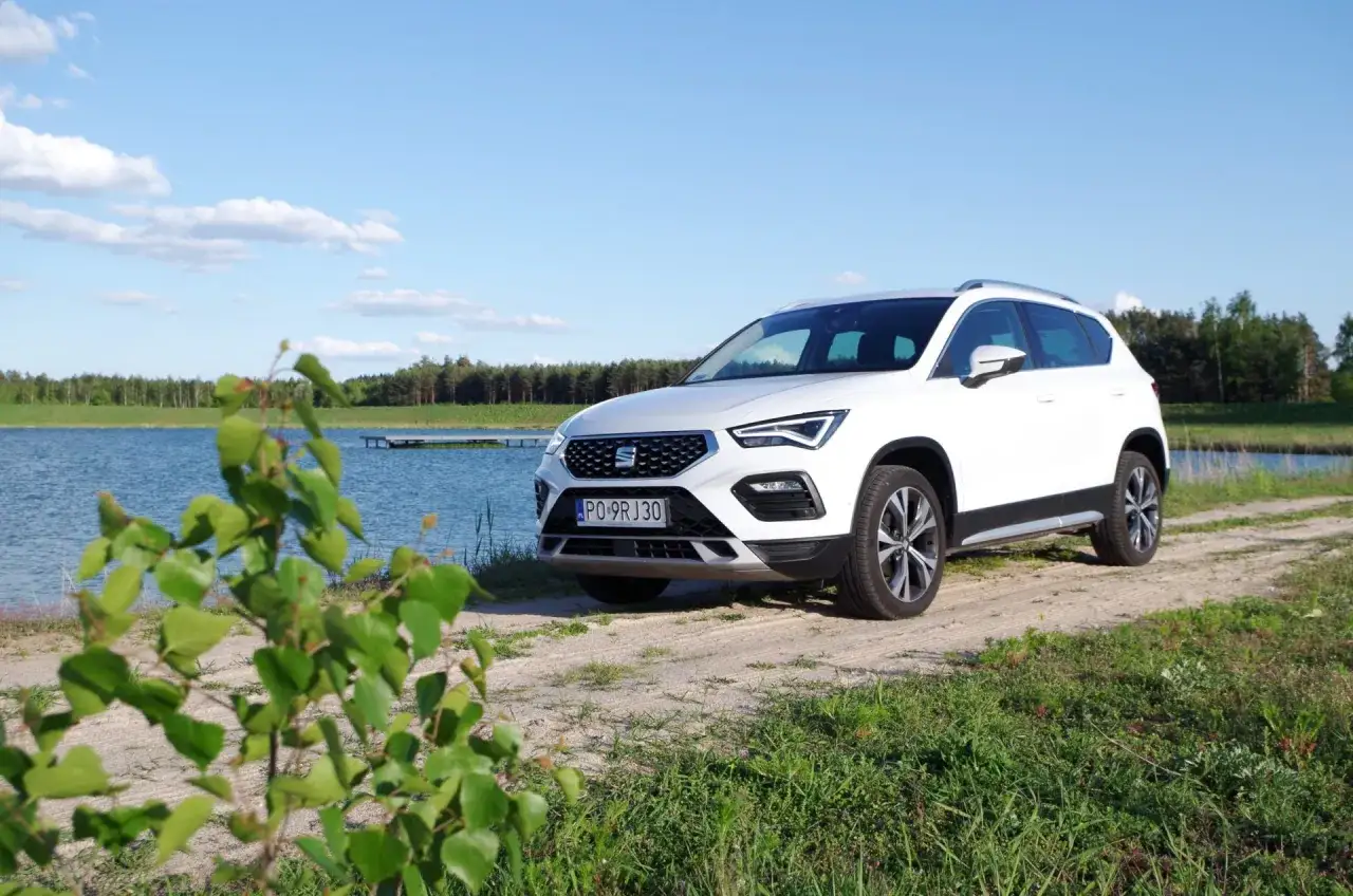 Biały Seat Ateca zaparkowany przy jeziorze, gotowy na letnią przygodę.