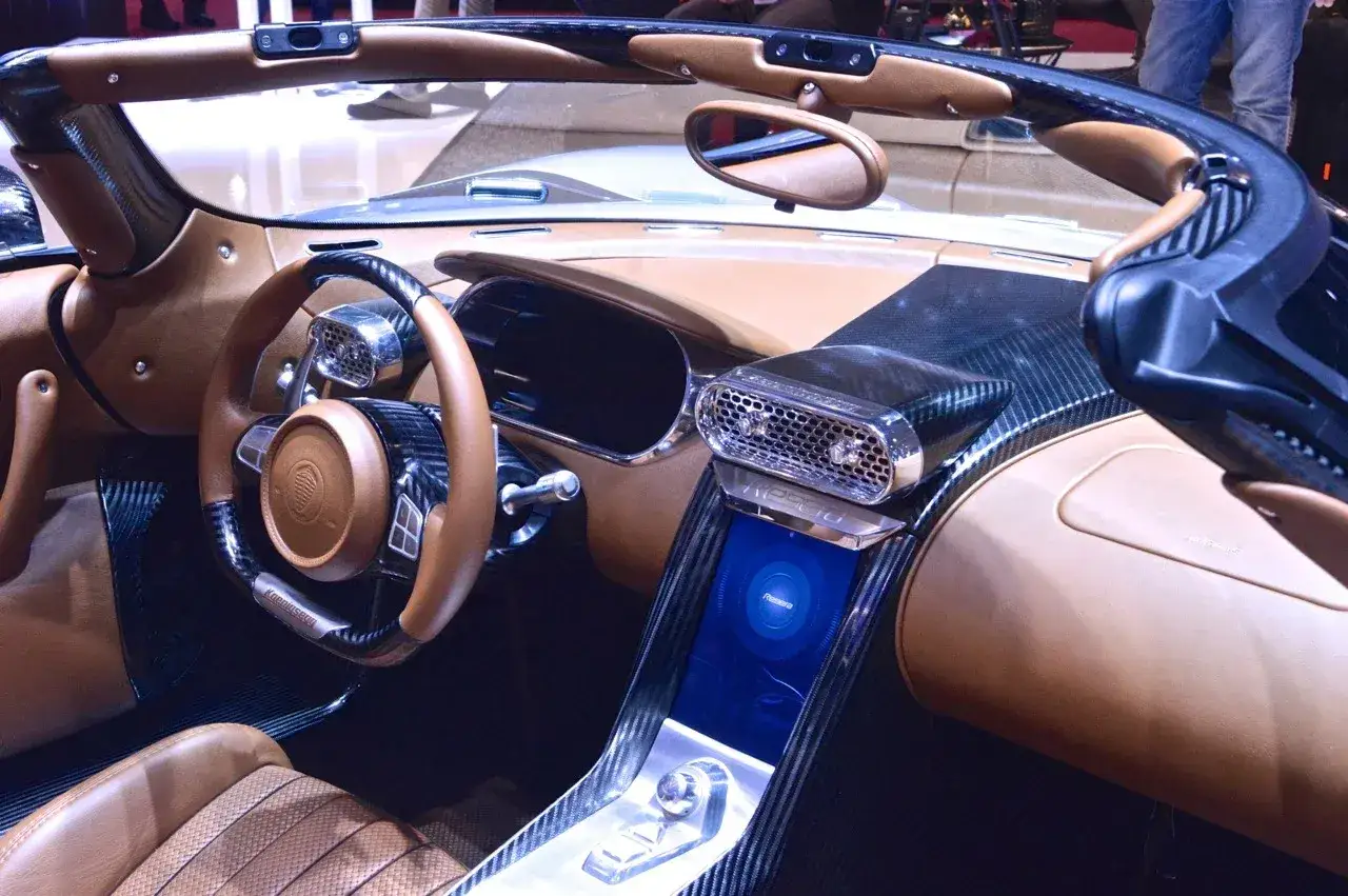 Wnętrze Koenigsegg Regera: brązowa skóra, włókno węglowe i nowoczesny ekran.