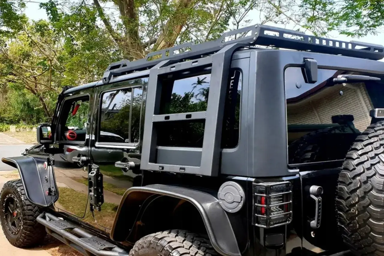 Czarny Jeep z bagażnikiem dachowym i drabinką. Przygotowany na wyprawę, ale wysokie koszty paliwa mogą pokrzyżować plany.