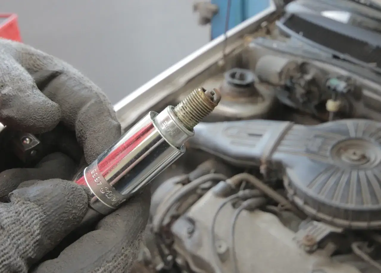 Ręka w rękawicy trzyma świecę zapłonową, potencjalną przyczynę błędu dtc p0300 w Renault.