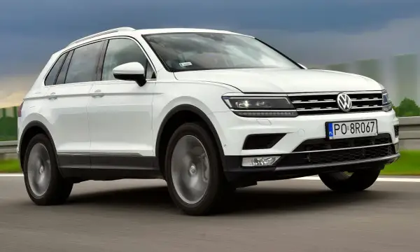 Biały Volkswagen Tiguan 2 jedzie po drodze.
