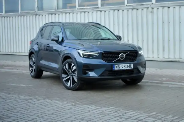 Elegancki, ciemnogranatowy Volvo XC40 2021 z charakterystycznymi światłami LED i felgami, zaparkowany przed budynkiem.