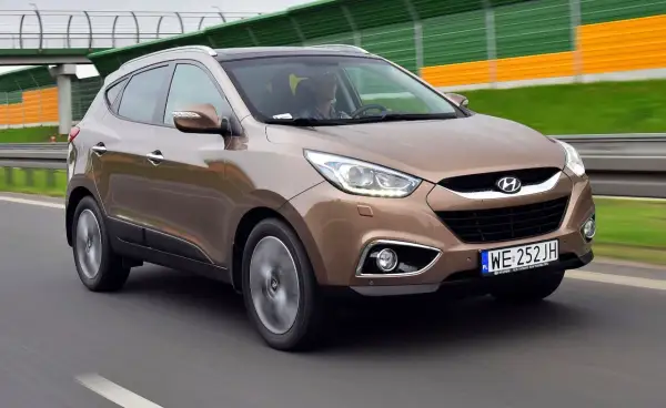 Brązowy Hyundai ix35 w ruchu drogowym, z widocznym kierowcą.