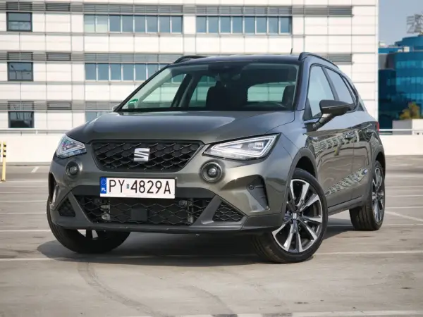 Szary Seat Arona 1.0 TSI zaparkowany przed nowoczesnym budynkiem.